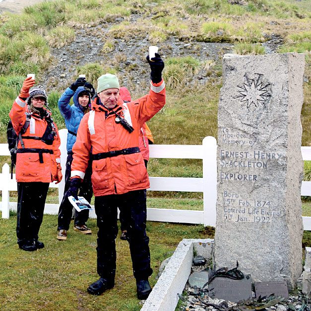 Eduardo Shaw raises a glass of Irish whiskey to toast famed Antarctic explorer Ernest Shackleton, who is buried at Grytviken. Photo by Tim Gallagher.