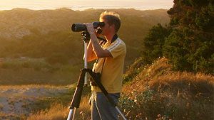 Guy looking through scope and using ebird to find birds near him