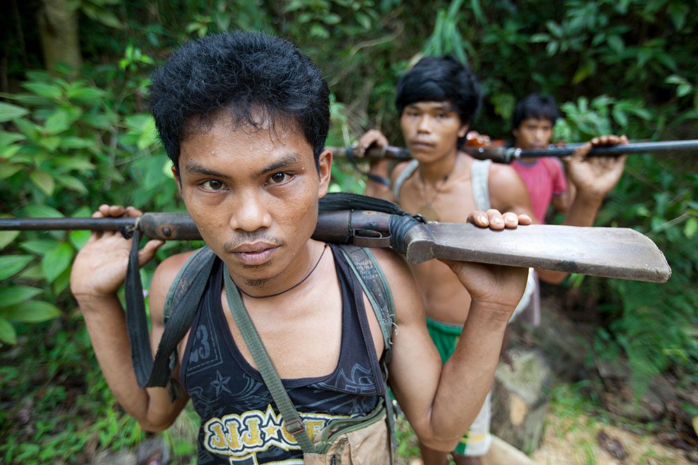 Hunters walk through forest near a Great Philippine Eagle nesting territory on Mindanao. Poaching is one of the biggest threats to eagles, but rural Filipinos here rely on resources from the forest for survival. Photo by Kike Arnal.