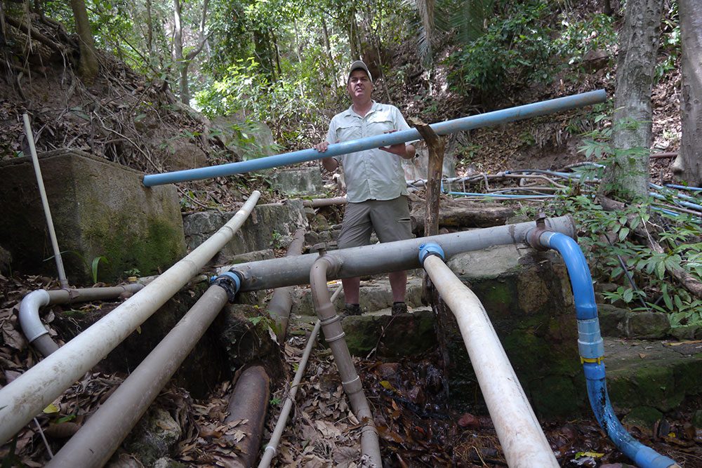 Alberto Campos stands in the forests at Batateiras Nascente, surrounded by water pipes brings water to the city of Crato. Photo by Gustave Axelson.