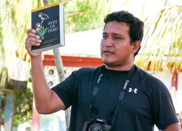 Birding guide César Sevillano shows a copy of the book Aves de Perú at a community event in Manatí I Zona. The Cornell Lab of Ornithology gifted a copy of the field guide to each participating community at the festival. Photo by Marilú López-Fretts.