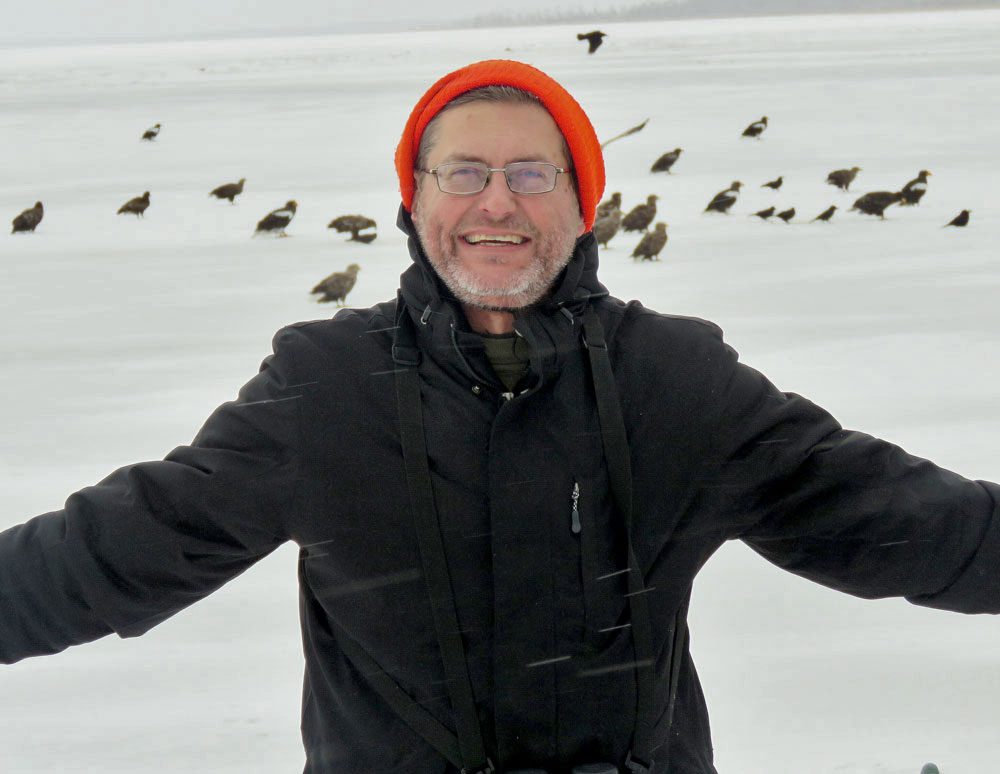 Tyler Hoar pictured standing in front of eagles on a snowy field.