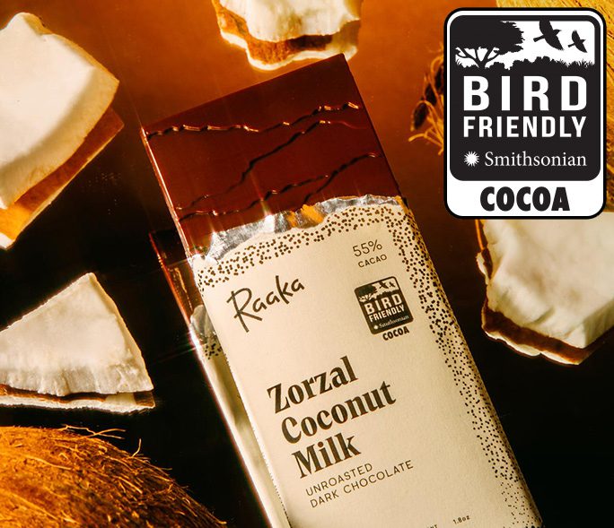 A partially-unwrapped Zorzal Coconut Milk chocolate bar surrounded by pieces of coconut.