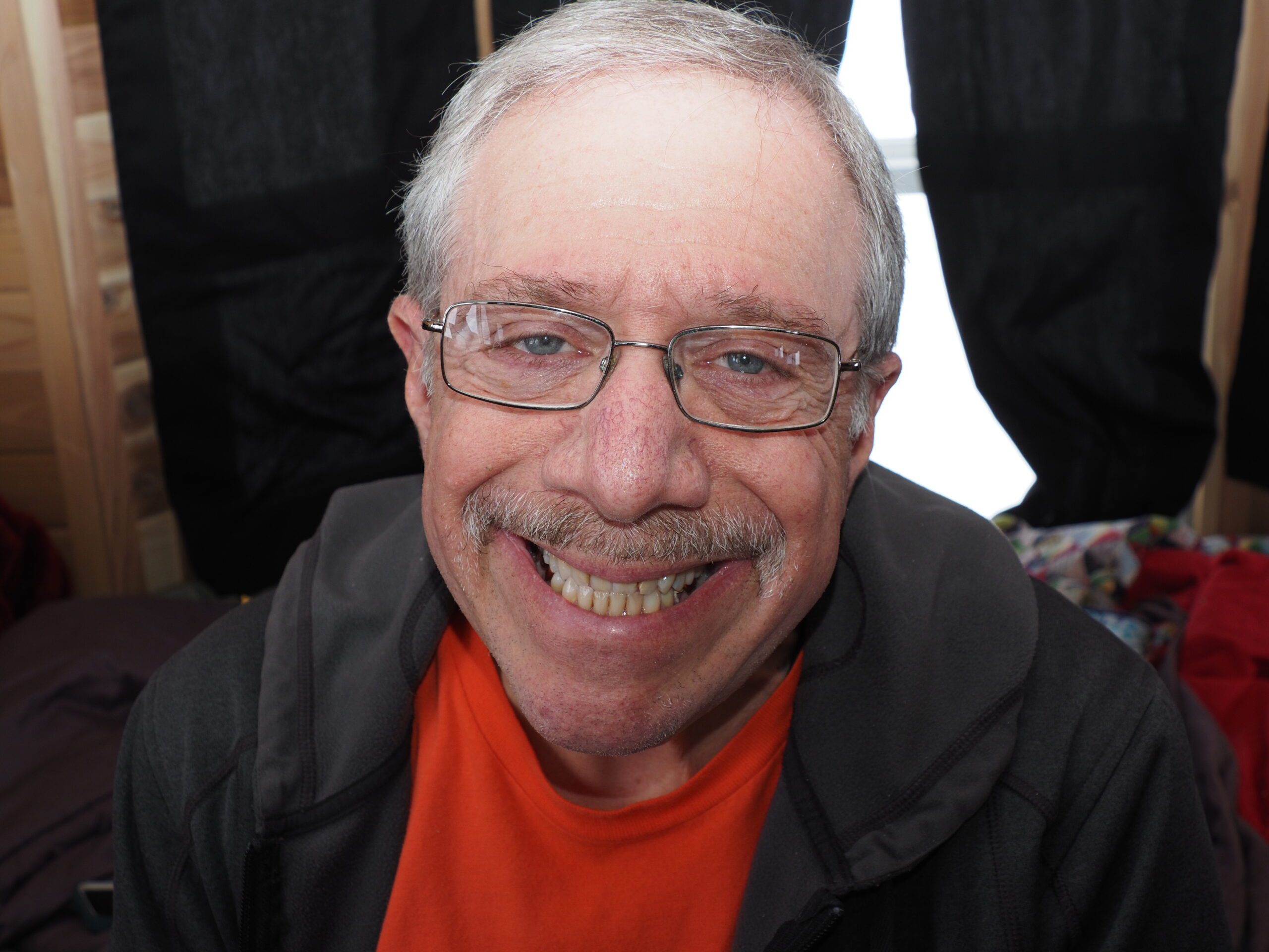 Man with glasses smiles at the camera.