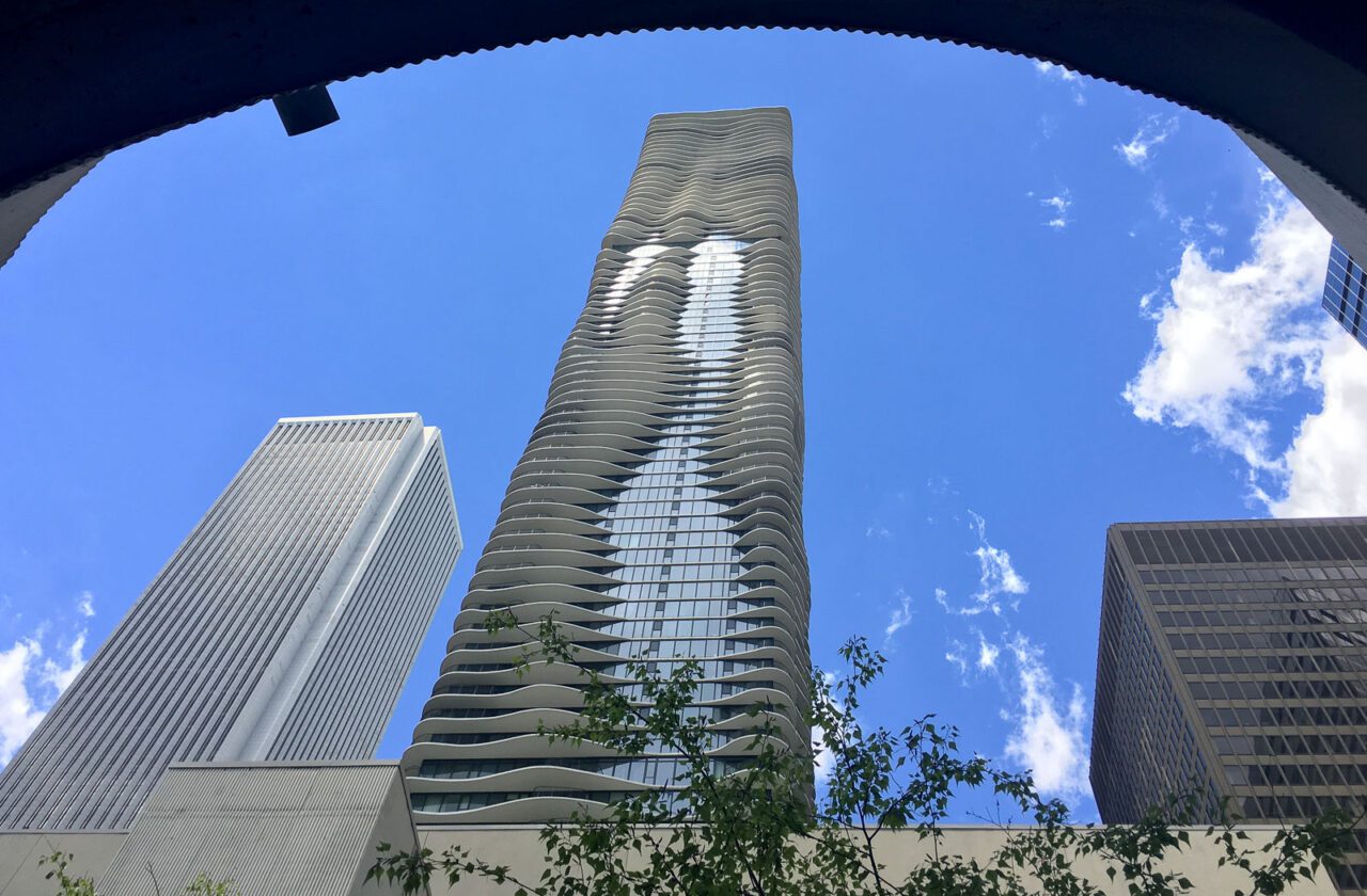 Several tall buildings, the one in the center showing a wavy design.